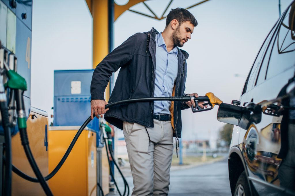 One man in a jacket filling up his car at a gas station