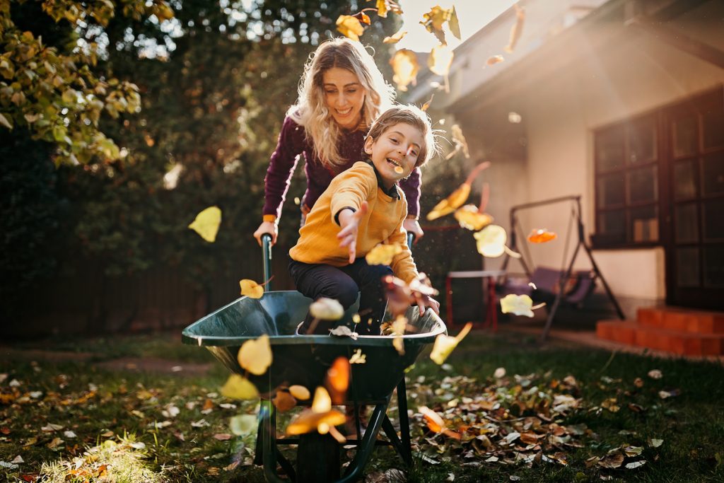 A mother and son play in the yard while doing fall home maintenance