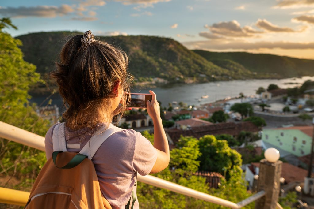 Young tourist woman taking photo of aerial view of Piranhas in Alagoas, Brazil