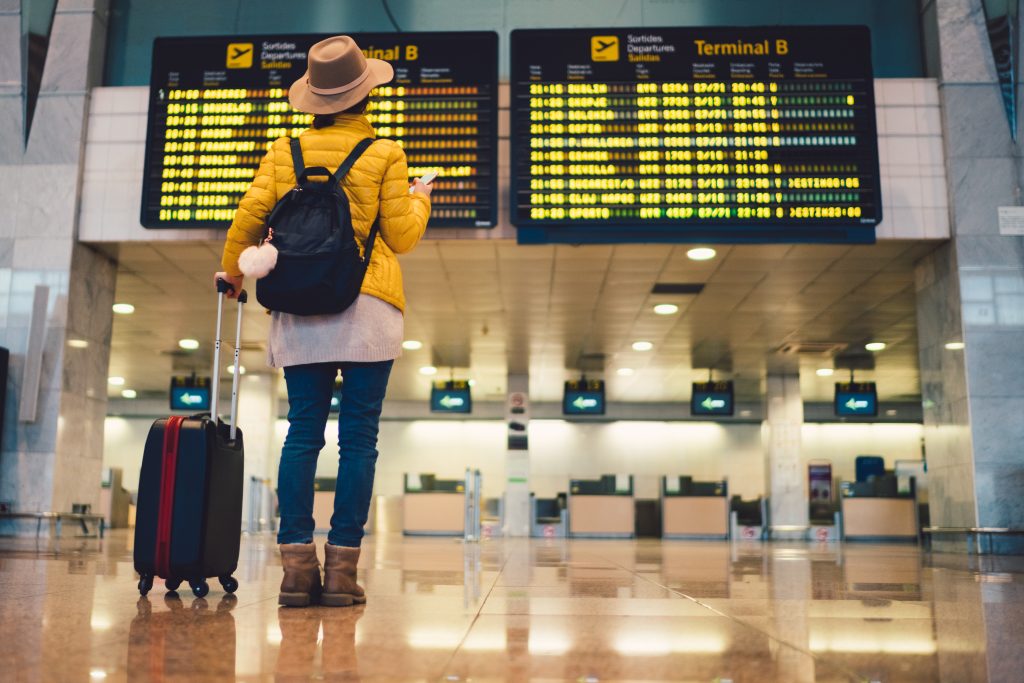 Young woman at the airport in Barcelona checking for the flight schedule on her travels