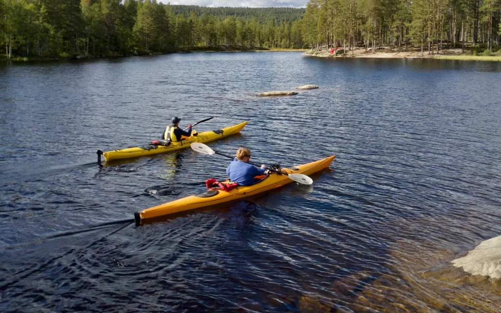 two kayakers paddle over summer calm waters