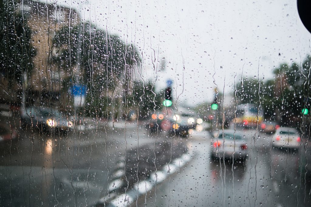 Rain drops blur a winod looking out on city traffic