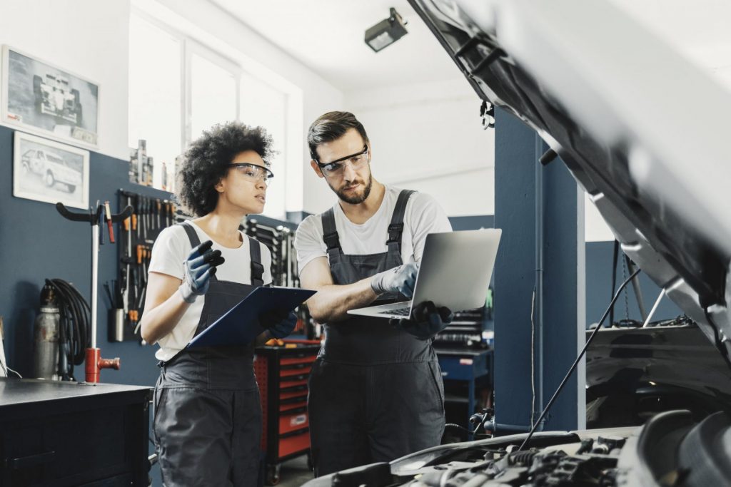 two mechanices perform car maintenance