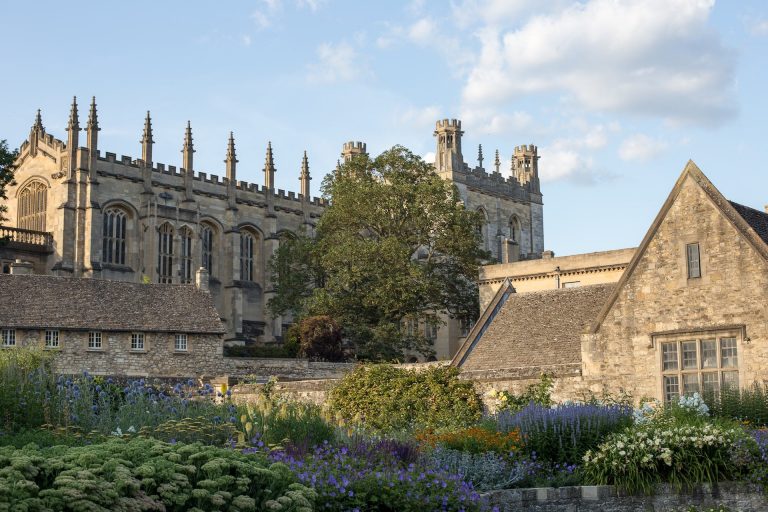 The castle like buildings of Oxford in England peak over roof tops and gardens