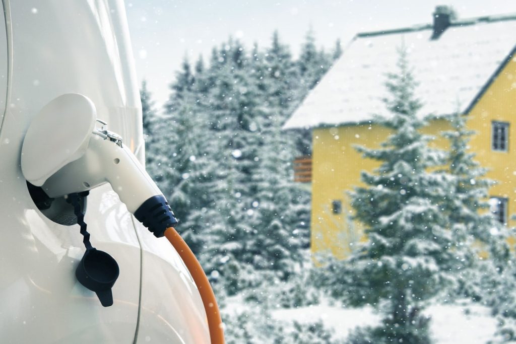 An electric car is covered in snow while charging