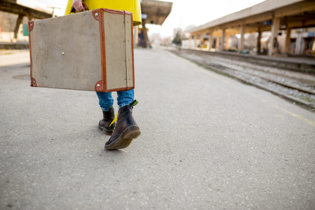 Woman waiting at the railway station with a suitcase.