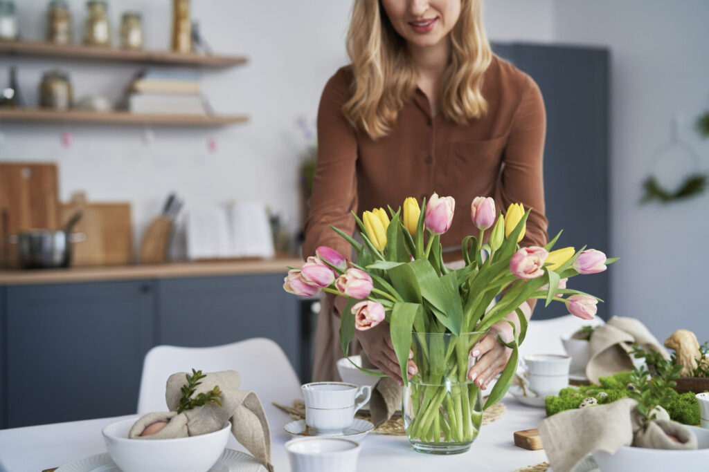 woman putting vase with fresh tulips on the table