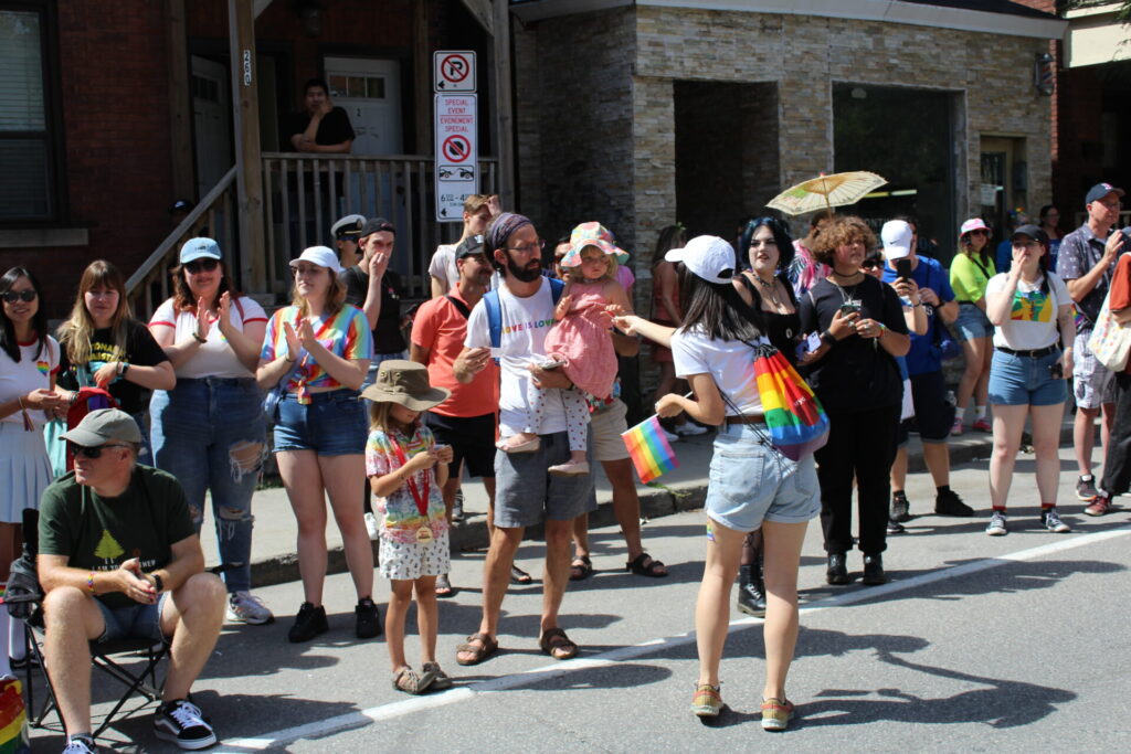 Woman with her back to the camera hands out tattoos to a family at the Ottawa Pride Parade