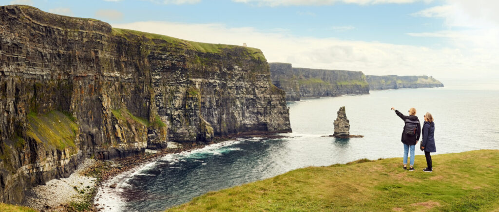 Two woman friends looking at coastline cliffs