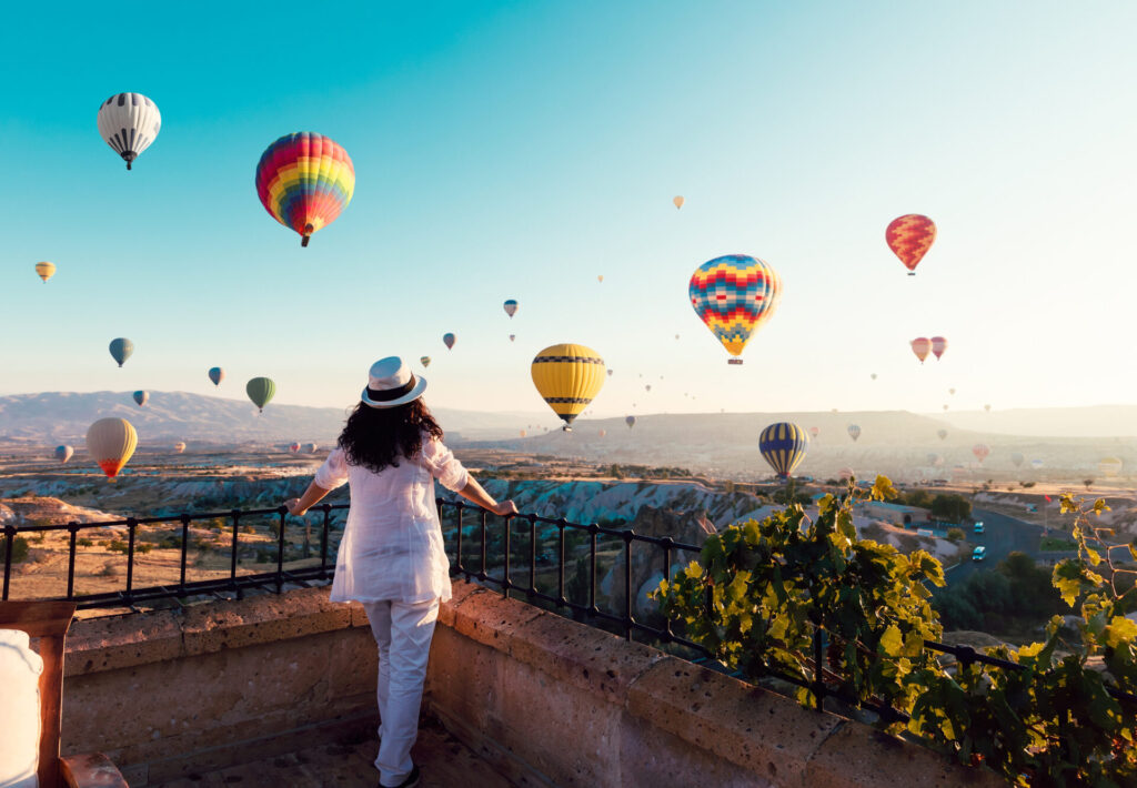 woman watching colorful hot air balloons flying over the valley at Cappadocia, Turkey.Turkey Cappadocia fairytale scenery of mountains. Turkey Cappadocia