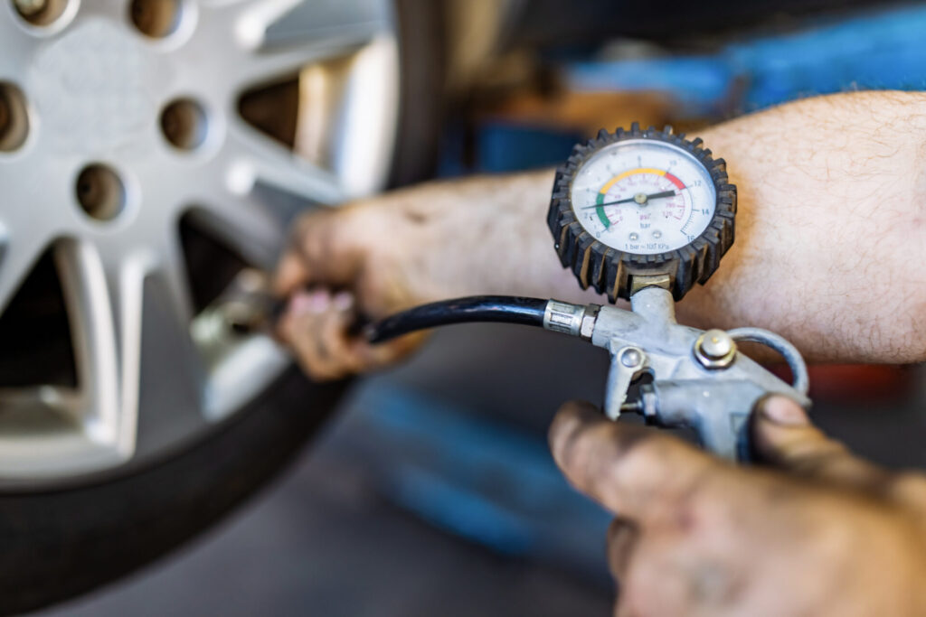 Close up of mechanic's hand checking the air pressure of a tyre in auto repair service