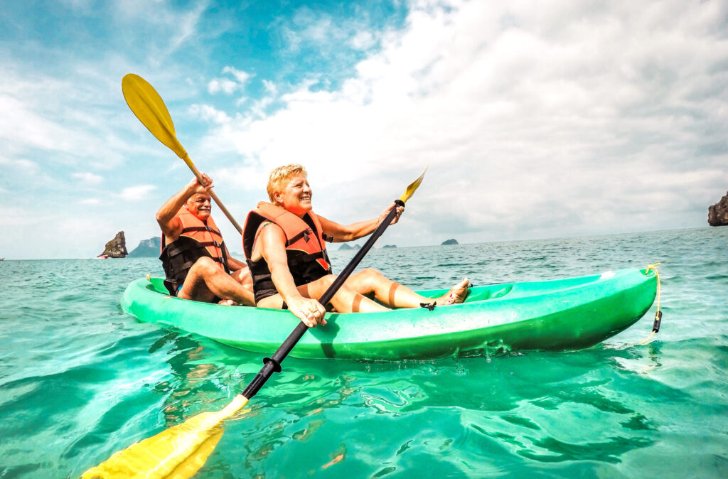 Happy retired couple enjoying travel moment paddling on kayak