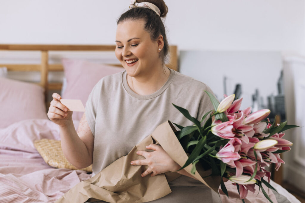 Woman Sitting on the Bed and Reading the Note She Got with the Flowers