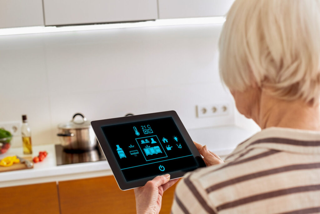 Senior woman standing controlling smart home on digital tablet back view screen close-up